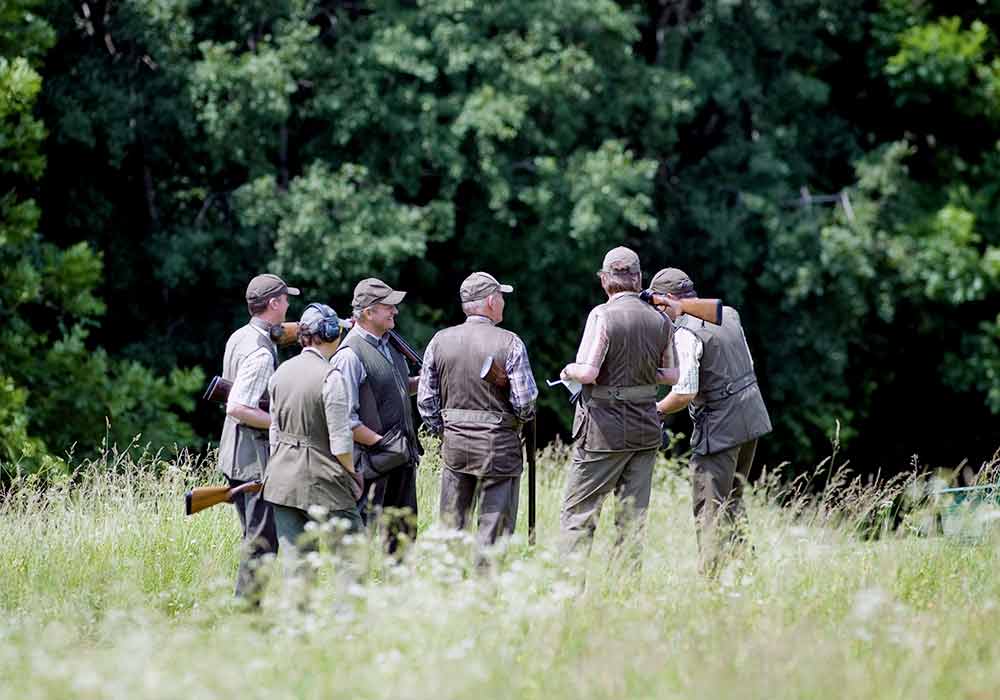 Eine Gruppe Herren mit Gewehr auf dem Gelände im Grünen